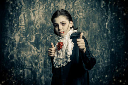 Portrait of a boy dressed in a costume of a vampire over grunge background. Halloween party.の写真素材