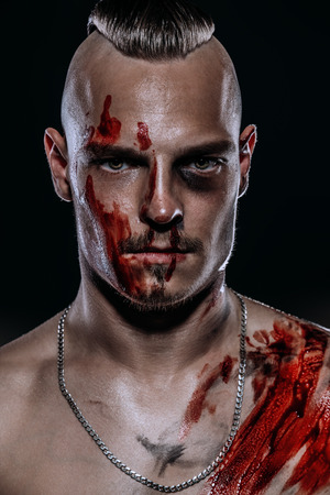 Fight club, MMA. Portrait of a bad guy fighter with a face in the blood, demonstrating his muscles and strength. Rocker, punk.の写真素材