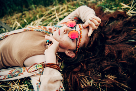 A portrait of a fashion female model lying on the grass. Contemporary bohemian style. Spirit of freedom. Fashion shot. Bohemian, bo-ho style.の写真素材