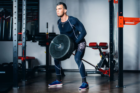 Muscular brutal man doing exercises with barbell in a gym. Health and sports concept.