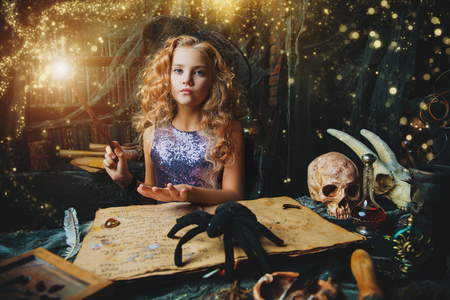 Beautiful charming little witch conjures in her lair. Halloween.の写真素材