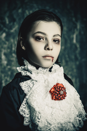 Portrait of a boy dressed in a costume of a vampire over grunge background. Halloween party.の写真素材