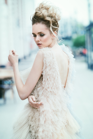 Beautiful young woman is walking around the city in an elegant fluffy dress. Beauty, street fashion.の写真素材