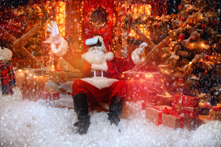 Santa Claus in virtual reality glasses is sitting on the porch. Christmas and New Year time.の写真素材