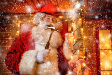 Portrait of Santa Claus in helmet repairing his home. Christmas and New Year concept.の写真素材