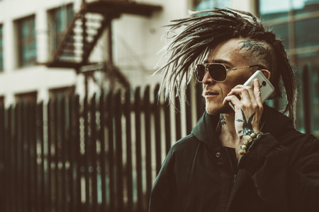 Portrait of a punk man on the street talking on the phone. Fashion, subculture.の写真素材