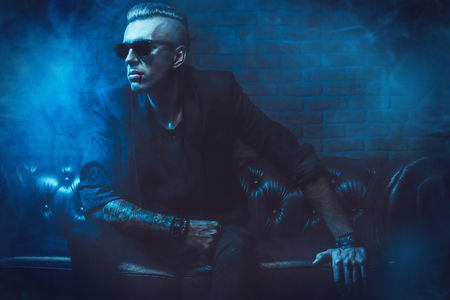 A vampire man in glasses is sitting in a dark room. Classic style. Beauty, fashion.の写真素材