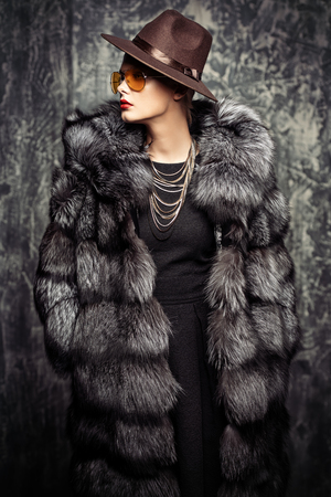 Gorgeous blonde woman posing in luxurious fur coat and a hat. Fashion, beauty. Studio shot.の写真素材