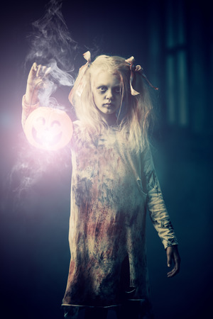A portrait of a scary zombie girl with pumpkin toy. Halloween. Horror movie.の写真素材
