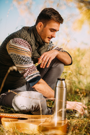 A handsome man is sitting in nature. Freedom, lifestyle, autumn.の写真素材