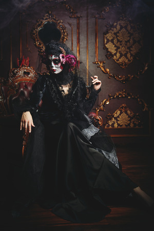 Calavera Catrina sitting in interior. Sugar skull makeup. Dia de los muertos. Day of The Dead. Halloween.の写真素材