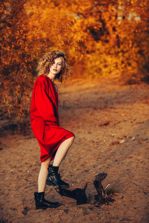 A portrait of a charming young girl with curly fair hair in a red dress. Fashion, beauty.の写真素材