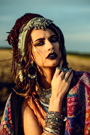 Magnificent fashion woman posing in boho style clothes in the rays of the sunset. Outdoor fashion. Gypsy style.の写真素材
