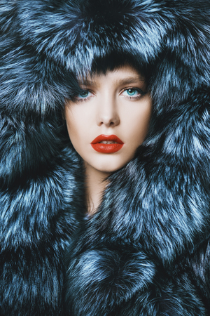 Portrait of a beautiful woman in luxurious fur coat posing in interior. Luxury, rich lifestyle. Fashion shot.の写真素材