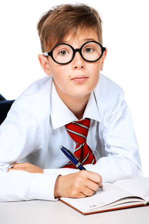 Portrait of emotional schoolboy in glasses with a book. Childhood, education. Kid, studying.の写真素材