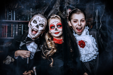 Halloween party. Cheerful children in carnival costumes celebrate halloween in the scenery of the witch's lair.の写真素材