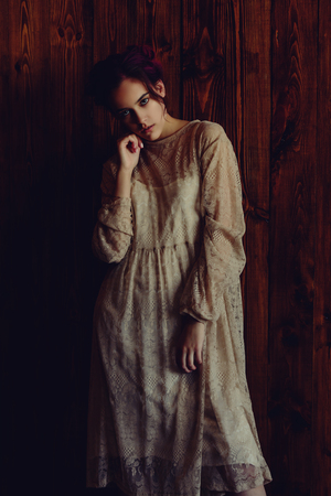 A pale girl I a white dress standing against a wall. Gothic style. Strong fashion feelingの写真素材
