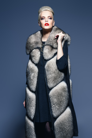 Portrait of a beautiful woman in a fur coat posing in a studio. Cool and strong. Fashion shot.の写真素材