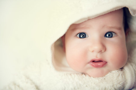 A close-up portrait of a funny baby wearing a hood. Family, parenthood. Goods for newborns.