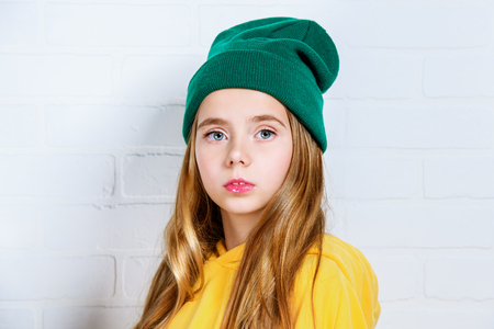 A close-up of a pretty girl in bright casual clothes posing in studio. Beauty, fashion for kids.の写真素材