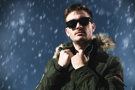 A handsome brutal man wearing a parka and sunglasses. Fashion for men. Autumn, winter.の写真素材