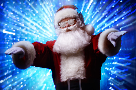 DJ Santa Claus in snowy glasses and headphones. Christmas songs and music. Disco lights in the background.の写真素材