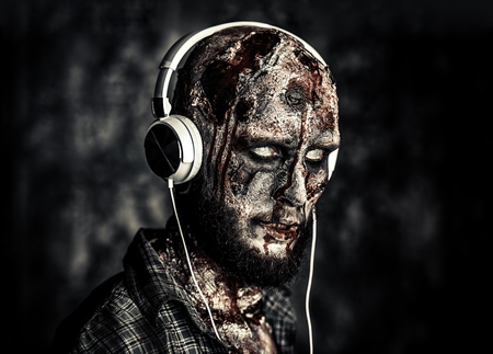 Creepy scary zombie is listening to music with headphones. Halloween. Horror film.の写真素材