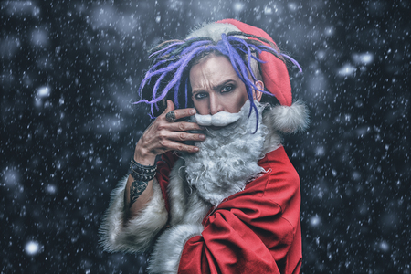 Portrait of a cool punk Santa Claus with bright dreadlocks over black background.の写真素材