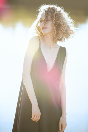 A close-up portrait of a beautiful young girl posing outside in a black dress. Fashion concept.の写真素材