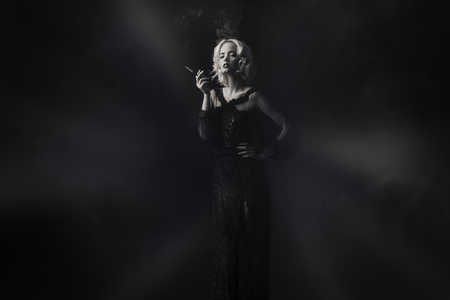 A beautiful blonde lady is smoking a cigarette. Evening dress. Fashion, beauty.の写真素材