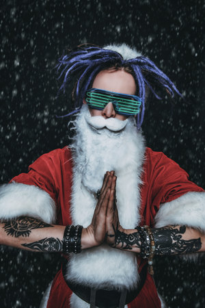 Portrait of a cool punk Santa Claus in luminous glasses with bright dreadlocks over black background.の写真素材