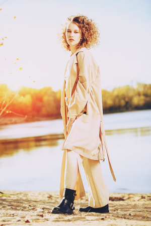 A charming young girl with curly fair hair in fashionable clothes. Fashion, beauty.の写真素材