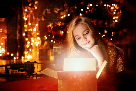 Pretty nine year old girl opens a gift box and surprises. Luxurious apartments decorated for Christmas. Merry Christmas and Happy New Year.の写真素材