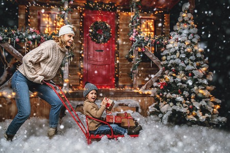 Mother and her son are playing in the yard of their house decorated for Christmas. Family miracle time. Merry Christmas and Happy New Year.の写真素材