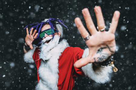 Portrait of a cool punk Santa Claus in luminous glasses with bright dreadlocks over black...