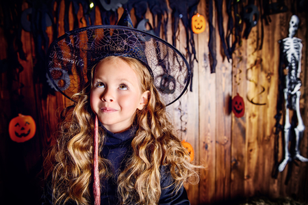 Portrait of a cute little child girl in a witch costume with magic wand. Happy Halloween!の写真素材
