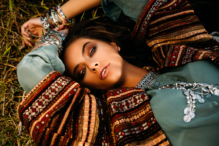 Beautiful hippie girl lying in a grass. Modern boho style. Beauty, fashion,の写真素材