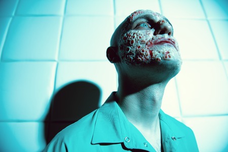 A close up portrait of a sick man in the blue light. Desparation, hopelessness.の写真素材