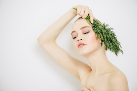 Beautiful young woman with bunch of parsley. Beauty, natural cosmetics concept. Spa, body care.の写真素材