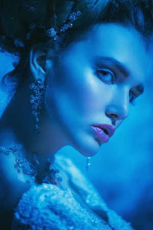 A close up portrait of a cold beautiful lady posing in the studio over the blue background. Beauty,cosmetics, hairstyle.の写真素材