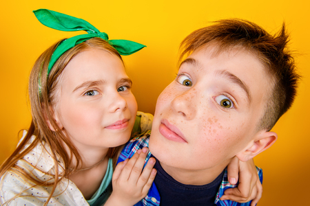 Portrait of two emotional children on a bright yellow background. Kid's fashion.の写真素材