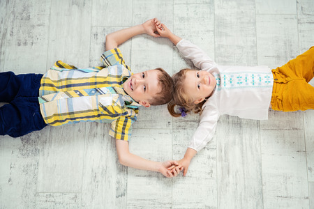 Two cheerful kids are lying on the floor. Fashion for kids.の写真素材