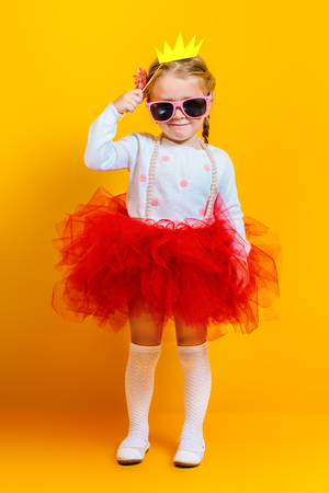 A portrait of a bright young pretty girl in skirt and sunglasses. Summer bright fashion for kids.の写真素材
