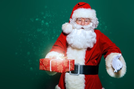 A portrait of Santa Claus holding a gift box. Merry Christmas and Happy New Year!の写真素材
