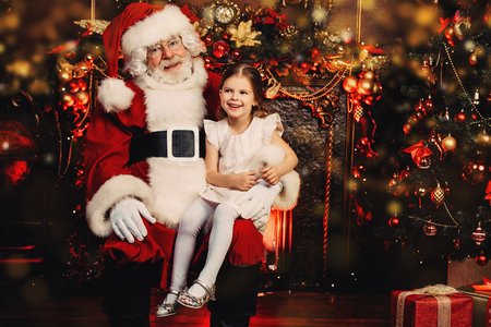 A happy young girl is with Santa Claus at home. Merry Christmas and Happy New Year.の写真素材