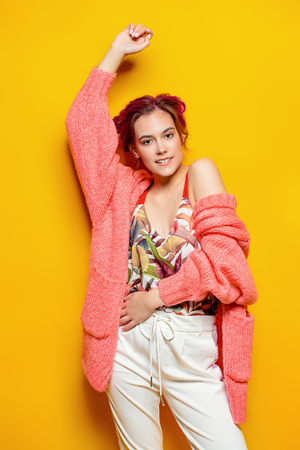 Beautiful girl with pink hair wearing bright clothes over yellow background. Bright style, fashion.の写真素材