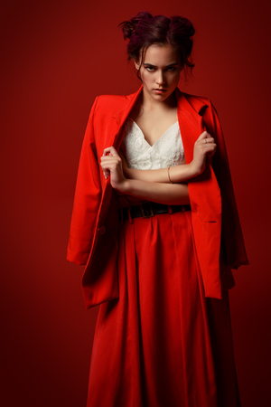Beautiful girl with pink hair wearing bright clothes over red background. Bright style, fashion.の写真素材