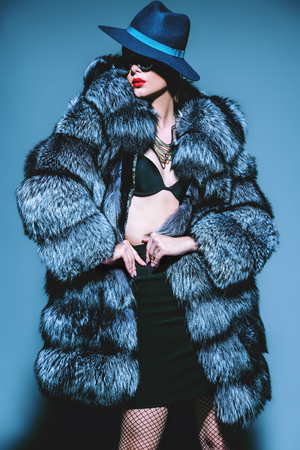 Gorgeous blonde woman posing in luxurious fur coat and a hat. Fashion, beauty. Studio shot.の写真素材