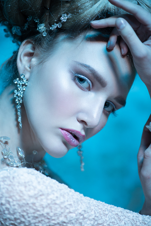 A close up portrait of a cold beautiful lady posing in the studio over the blue background. Beauty,cosmetics, hairstyle.の写真素材
