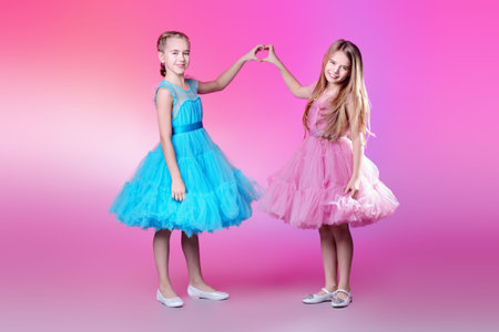 Two pretty little girls dressed in beautiful festive dresses. Kid's fashion concept.